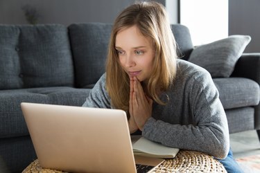young woman having video teletherapy on laptop next to couch