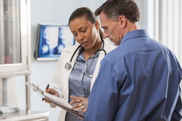 A female doctor showing a normal cholesterol levels by age chart to a male patient