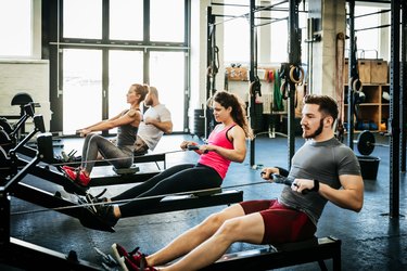 Fitness Enthusiasts Exercising Using Rowing Machines