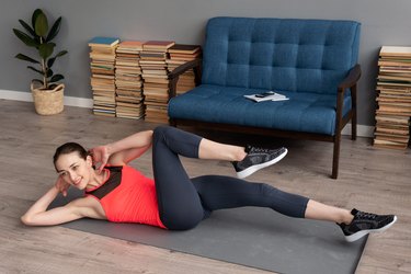 Fitness woman doing bicycle crunch workout on mat at home