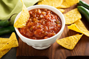 Spicy salsa with tortilla chips on a wooden serving board