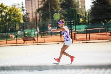 Female tennis player hits the ball with forehand .