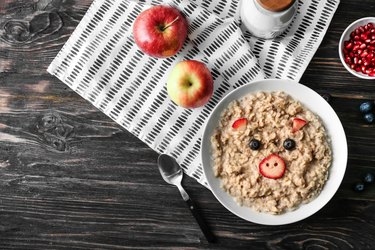 Plate with creative oatmeal for children on dark wooden table