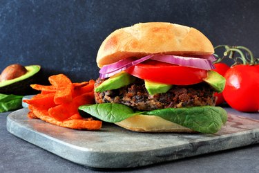 Veggie burger with sweet potato fries on a dark background