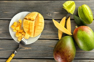 Composition with fresh mango on wooden background