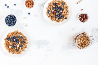 Flat lay, top view of two bowls of cereal topped with nuts and berries