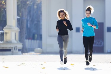 Two focused young women running listening to music