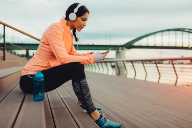 woman taking a break after jogging to drink and track water