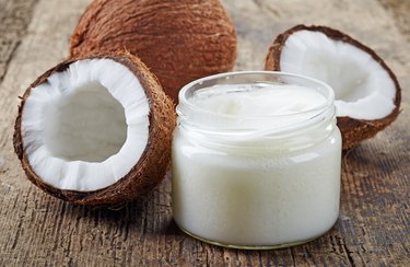 Fresh coconuts and a jar of coconut oil on a wooden table, as a home remedy for sunburn