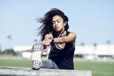 woman doing stretching exercises outside with headphones