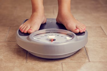 a close up of feet on a bathroom scale on a tile floor