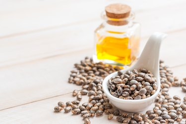 Castor oil with beans on wooden surface