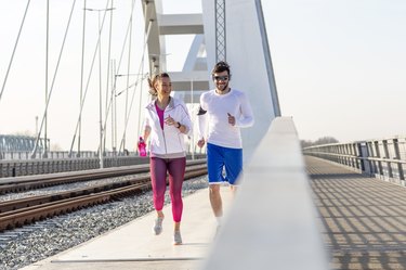 Couple jogging at the bridge with headphones