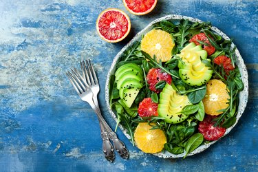 Citrus salad with mixed greens and blood orange. Vegan, vegetarian, clean eating, dieting, food concept. Blue stone background.