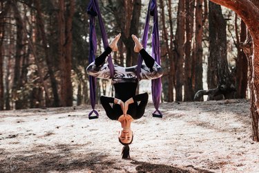 Fly yoga. Woman athlete feels satisfied and relaxed enjoying a yoga exercises in the forest