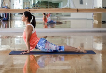 Side view of woman doing upward facing dog position while exercising in gym