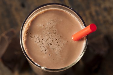 Top view of a chocolate protein shake in a glass with a straw