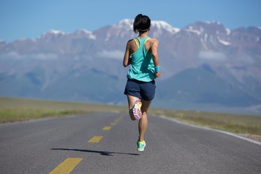 健身女跑步者在道路上跑步的后视图