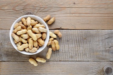 Roasted peanuts in bowl on wooden table