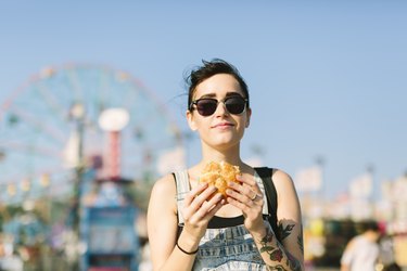 A young woman eating a hamburger at an amusement park