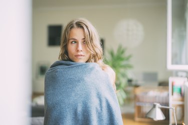 Portrait of young woman wrapped in a blanket at home