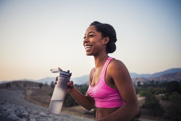 Woman holding a water bottle and training for a 5K