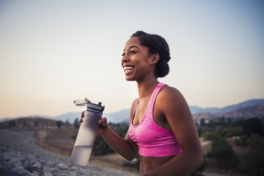 Happy female runner holding water bottle