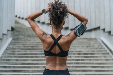 Rear view of woman runner tying her hair and getting ready for another run outdoors