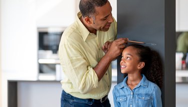 Father measuring his daughter against the wall