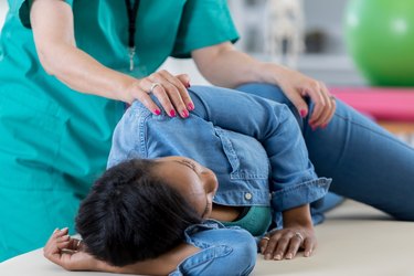 Unrecognizable chiropractor adjusts a mid adult woman