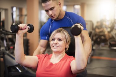 Woman doing shoulder exercise with a trainer during a beginner strength-training workout