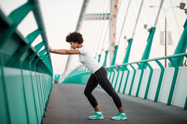 Athletic, young woman exercising on city bridge
