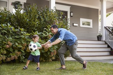 person playing soccer in garden with their child