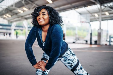 A woman in athletic clothes stretching outdoors