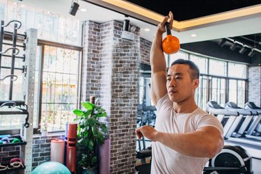 Muscular man is working out with kettlebell