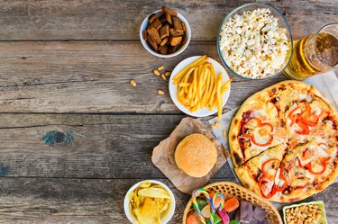 Fast food on old wooden background. Concept of junk eating. Top view.