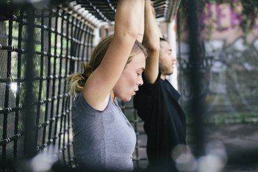 Young Woman Exercising With Colleague Outdoors