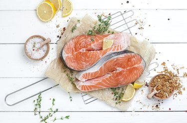 Raw salmon steak on white wooden background top view