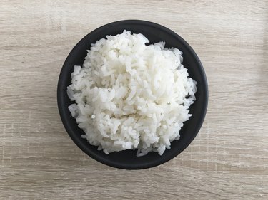 A black bowl of slow cooker rice on wooden table.