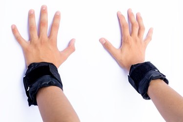 Pair of hands isolated on white of a male wearing black colored wrist weights in his hands.