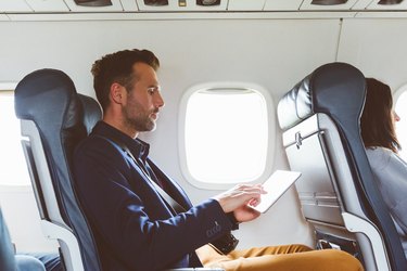 Businessman using digital tablet in airplane