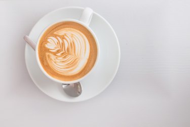 White cup of hot cappuccino art coffee on wooden table