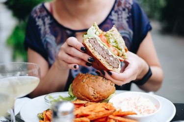 Midsection Of Woman Holding a Burger At Restaurant