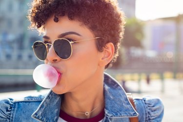 Woman blowing bubble gum balloon to get the benefits of chewing gum