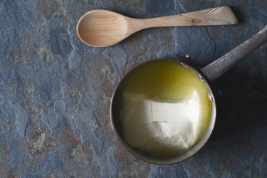 Melted butter in the stewpan on stone background top view