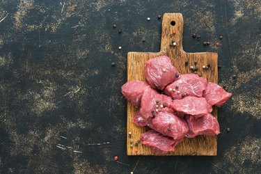 Raw beef meat sliced on a dark background. Top view, copy space.