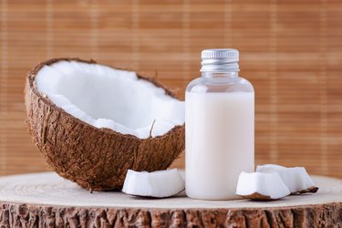 cosmetic bottle and fresh organic coconut for skincare, natural background