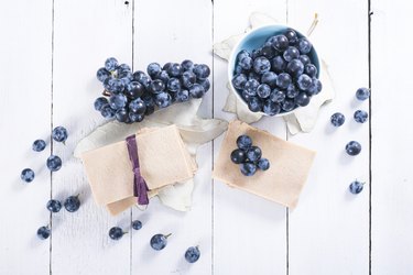 Bowl and bunch of black grapes to make slimming grape juice on white wooden table with soap