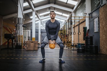 Man doing a kettlebell superset workout in the gym