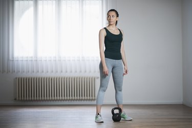 女人做家庭力量训练workout using a kettlebell